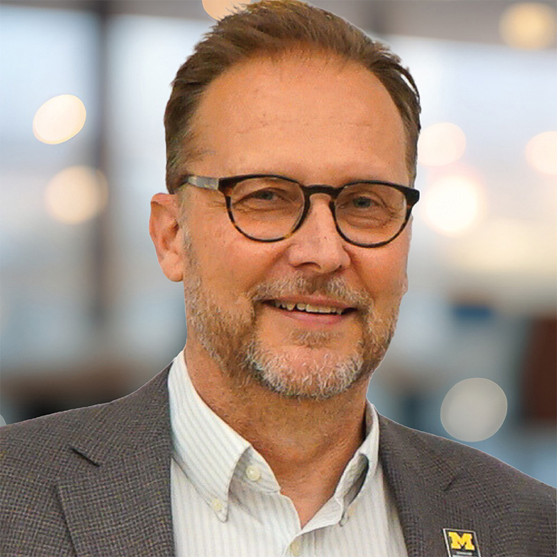 Kurt skifstad headshot a man with light brown hair, glasses and a goatee wearing a brown jacket with a CFE lapel pin