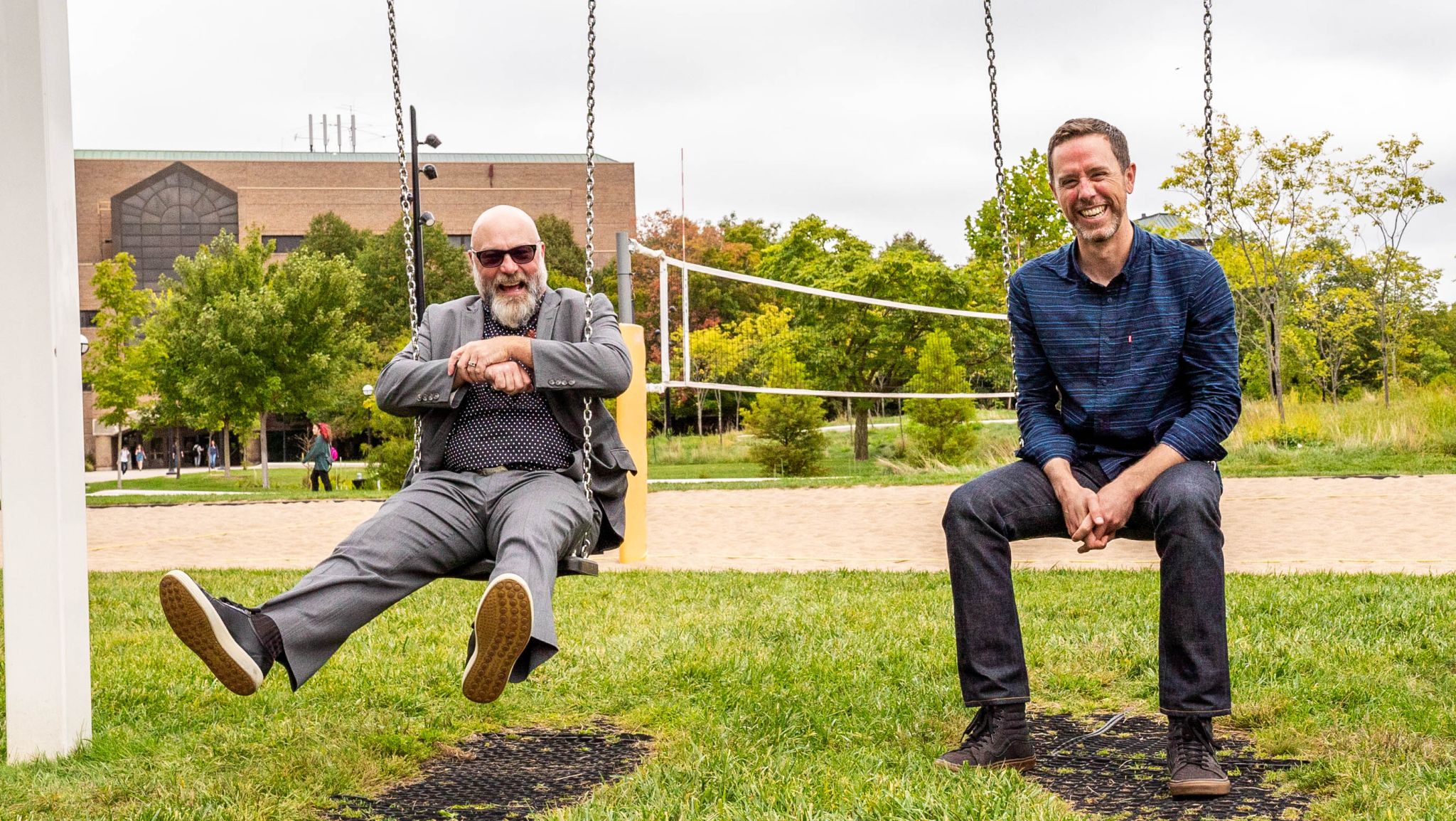 Michael J. MCFall and Brian Hayden sitting on swings on the University of Michgian's North Campus Grove