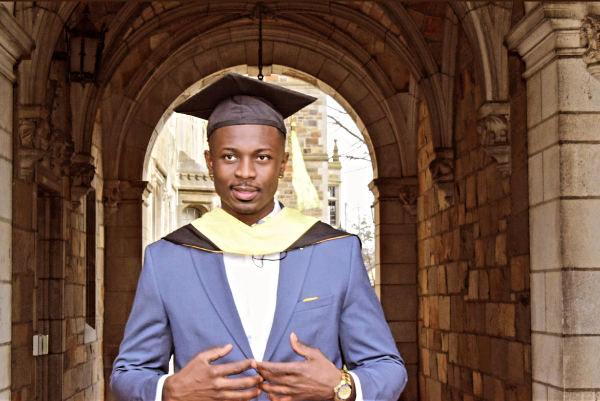 Samuel poses in a graduation cap in the Law Quad.