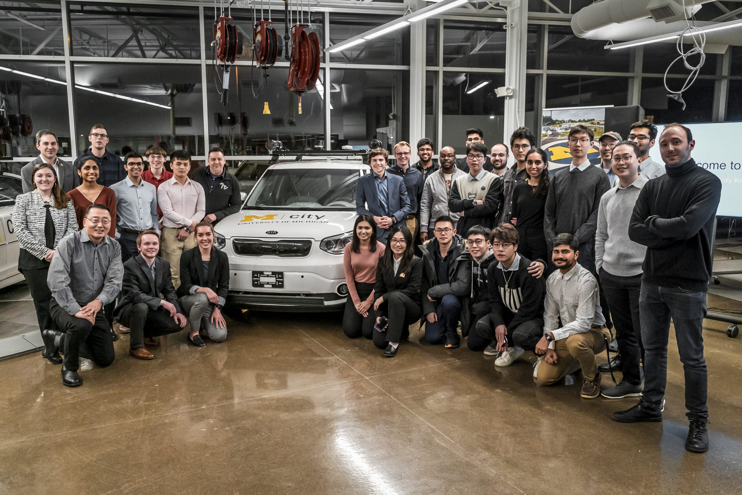 TechLab students smile while standing next to an autonomous vehicle