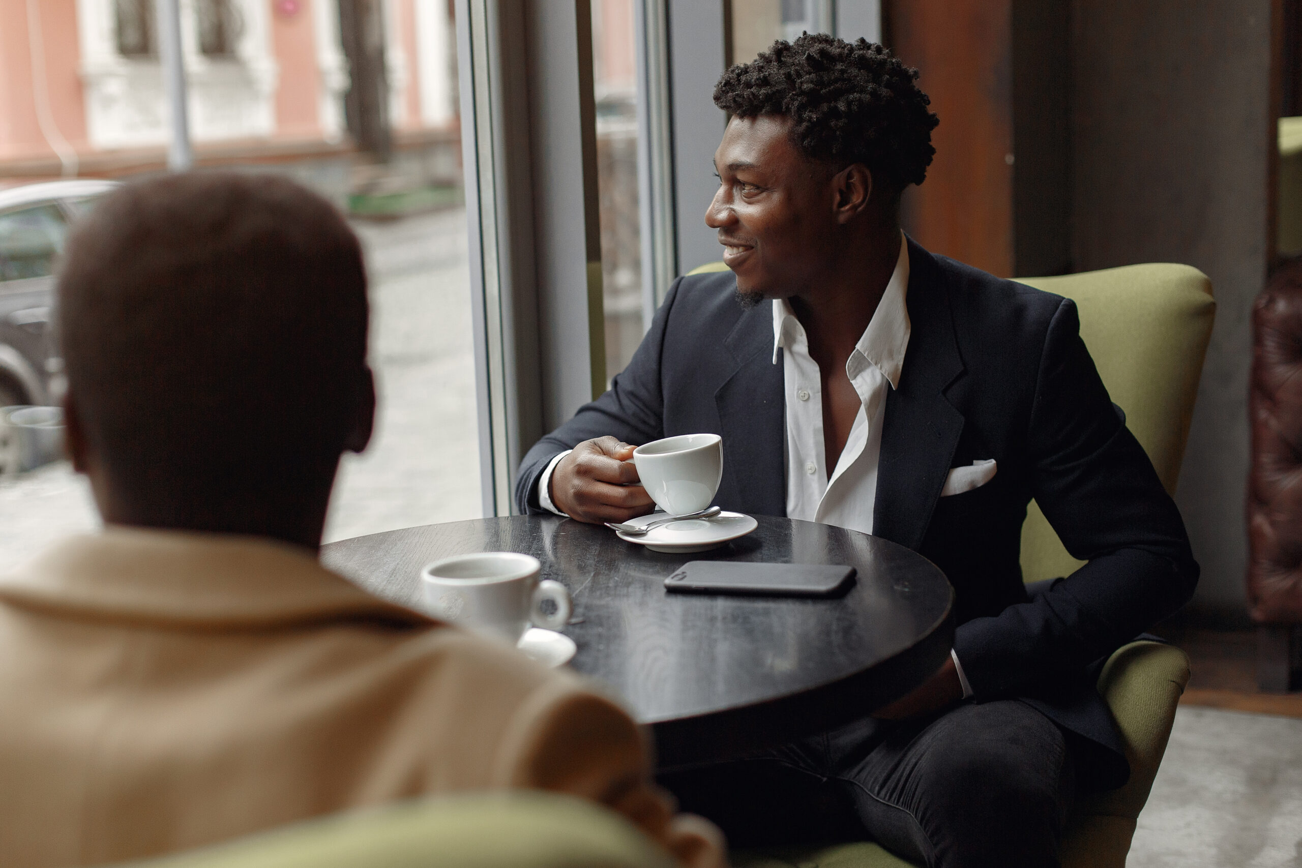 Black men in a cafe. Guys drinking a coffee. Businessman in a black suit.