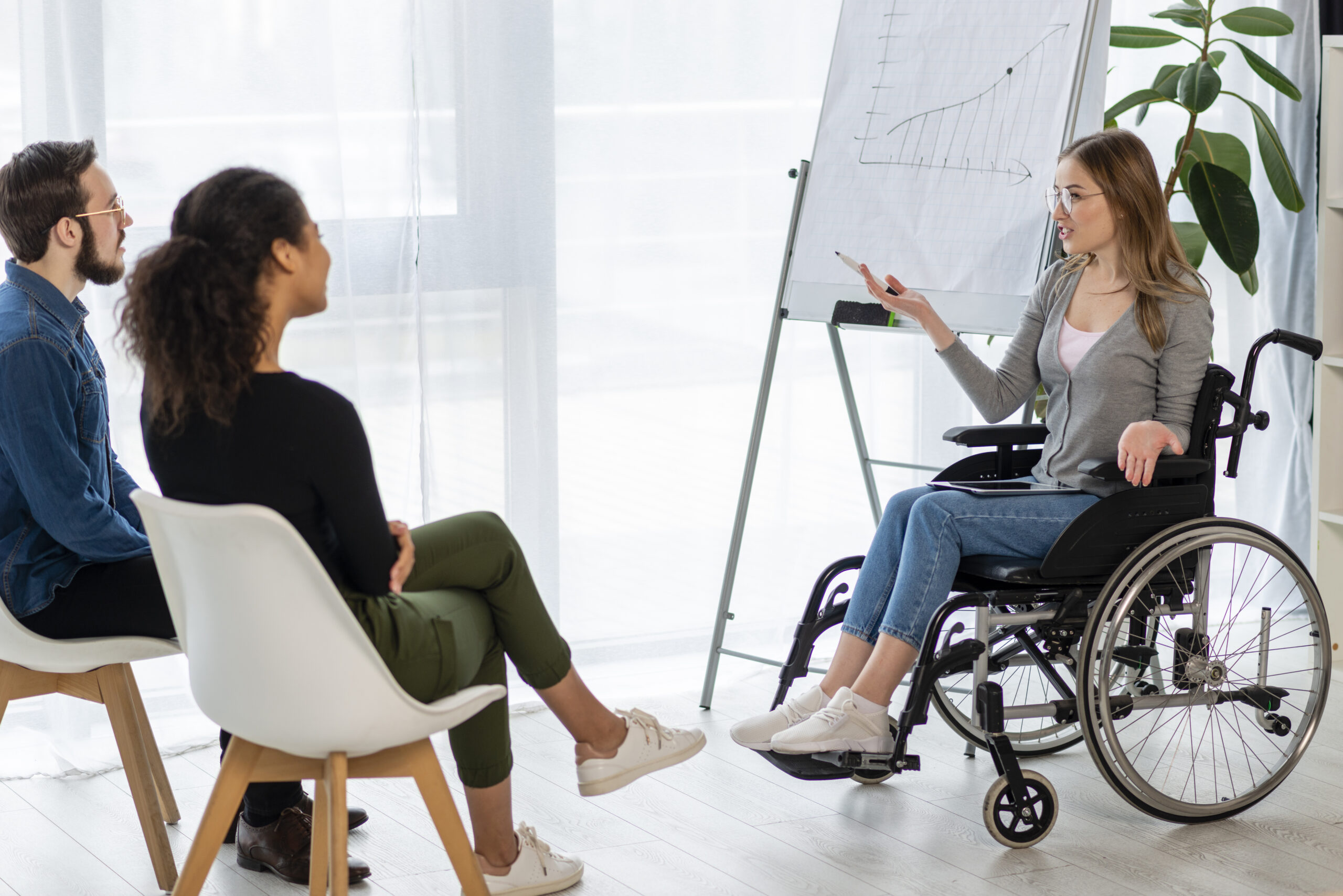 woman in wheelchair giving presentation to co-workers