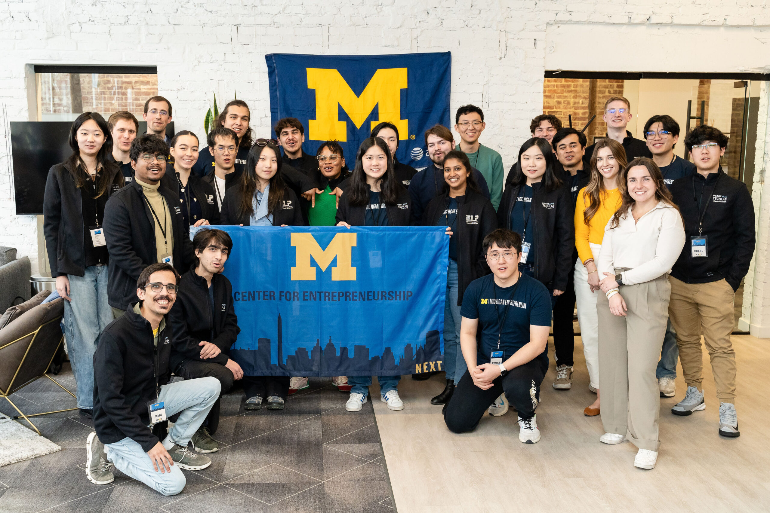 A large group of students pose with a flag that reads 