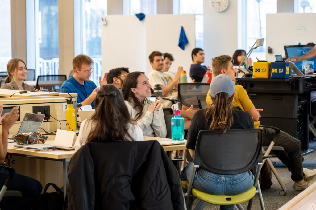 Group of students in a classroom setting listening to presentations