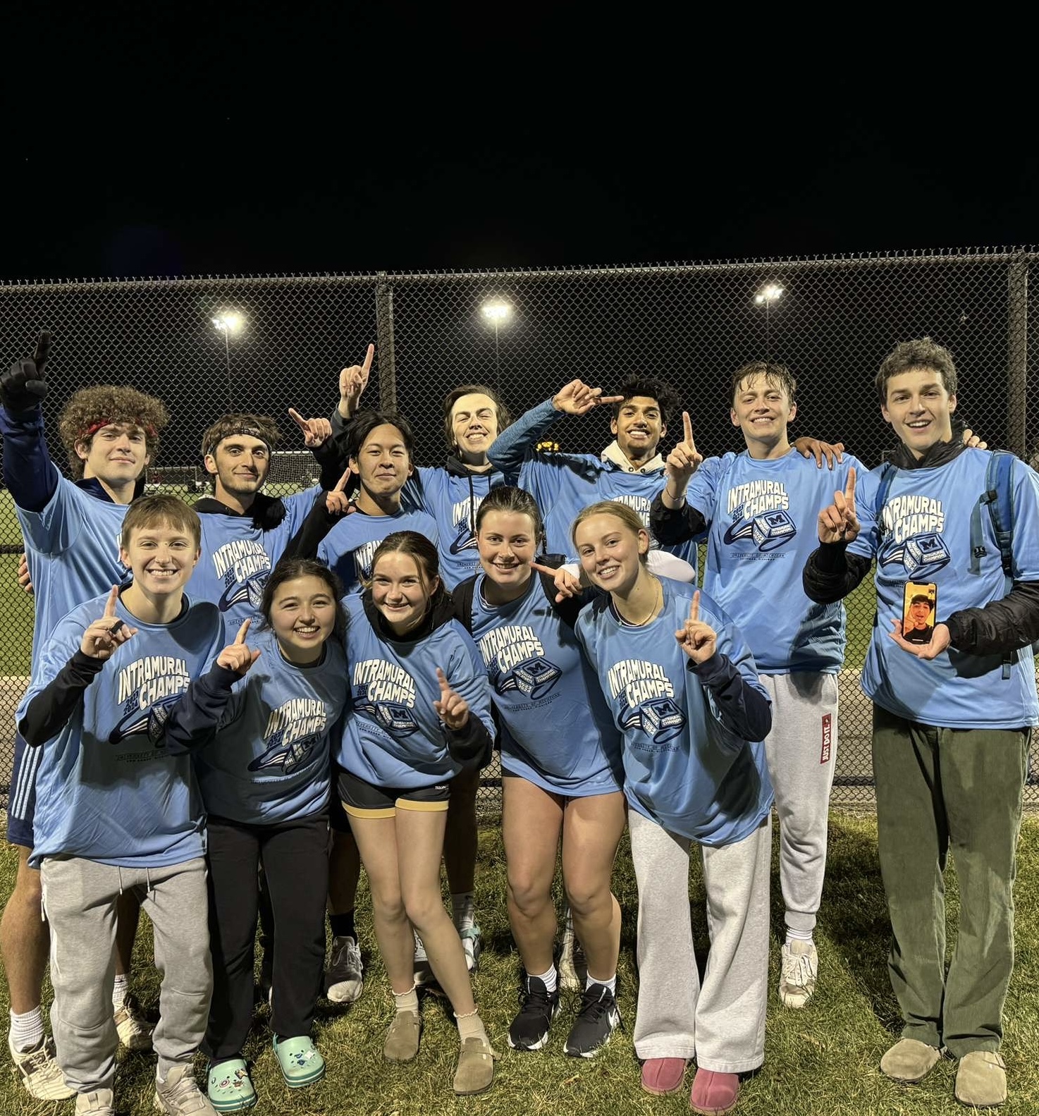 Dom poses with his intramural sports team. They are holding up "ones" with their fingers, signifying their win as IM champs.