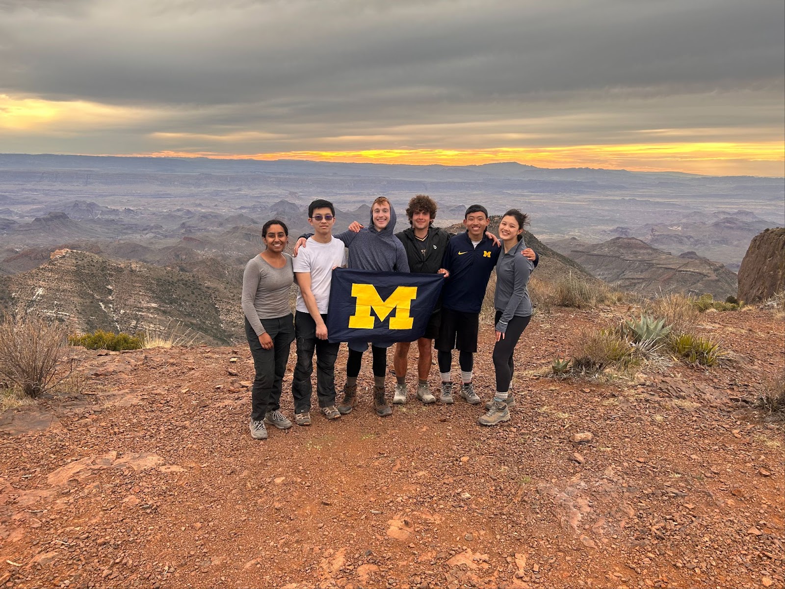 Dom poses with a Michigan flag with fellow students on a mountain.