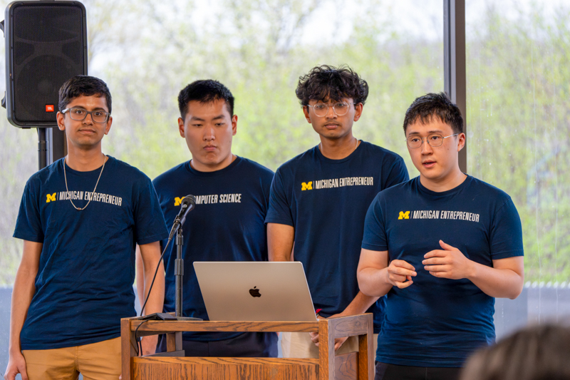 four students in Michigan Entrepreneur shirts presenting a project