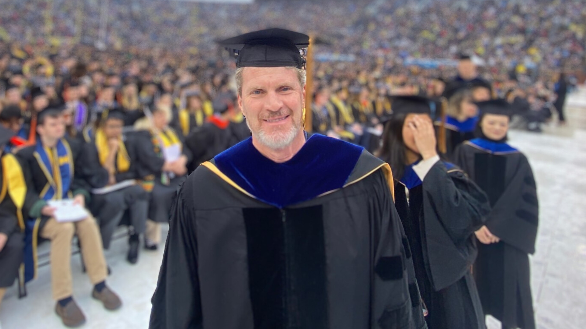 Chris Quinn wears a cap and gown during U-M graduation.