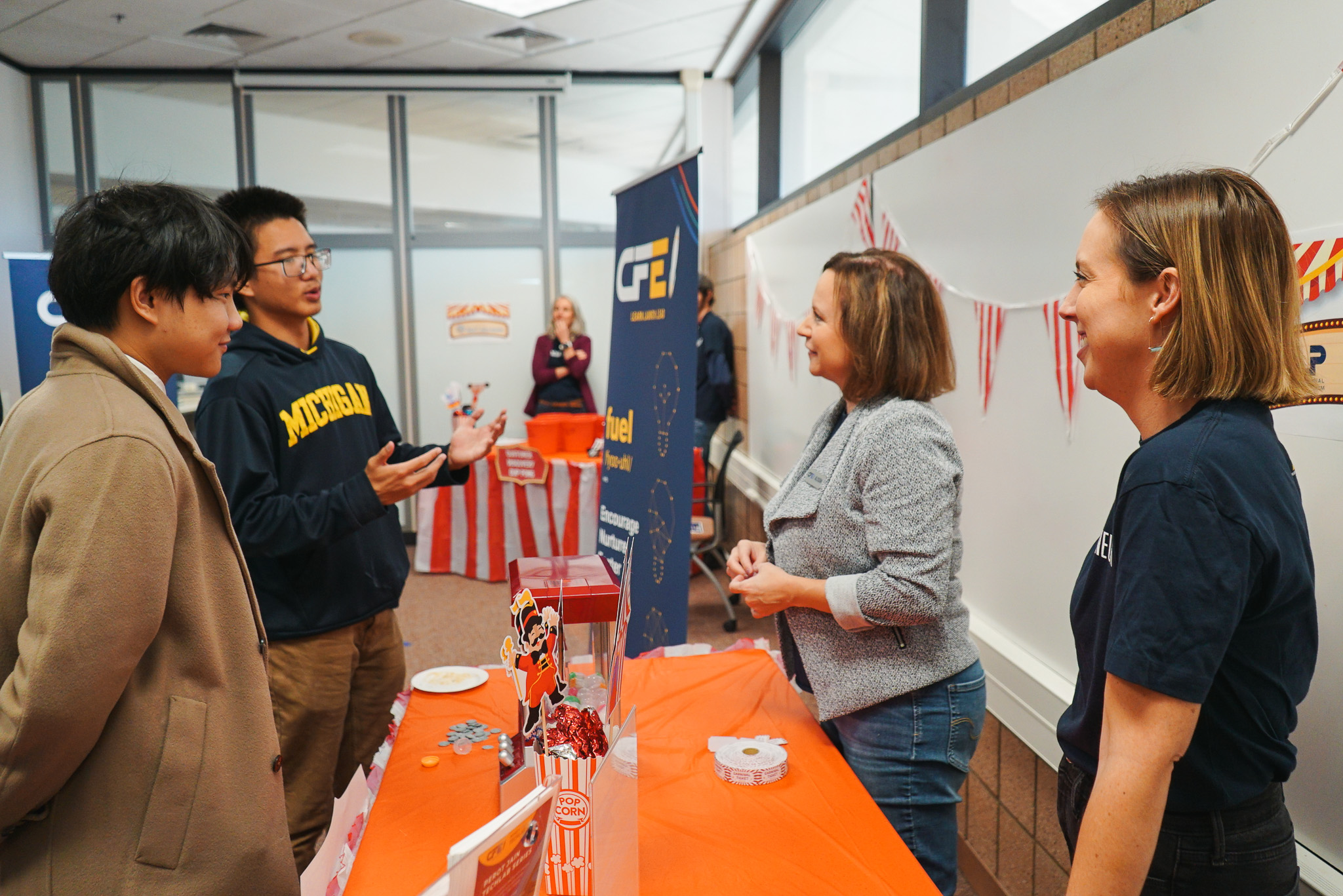 Students speak with two members of the entrepreneurial practice programs team at the CFE Open House Carnival.