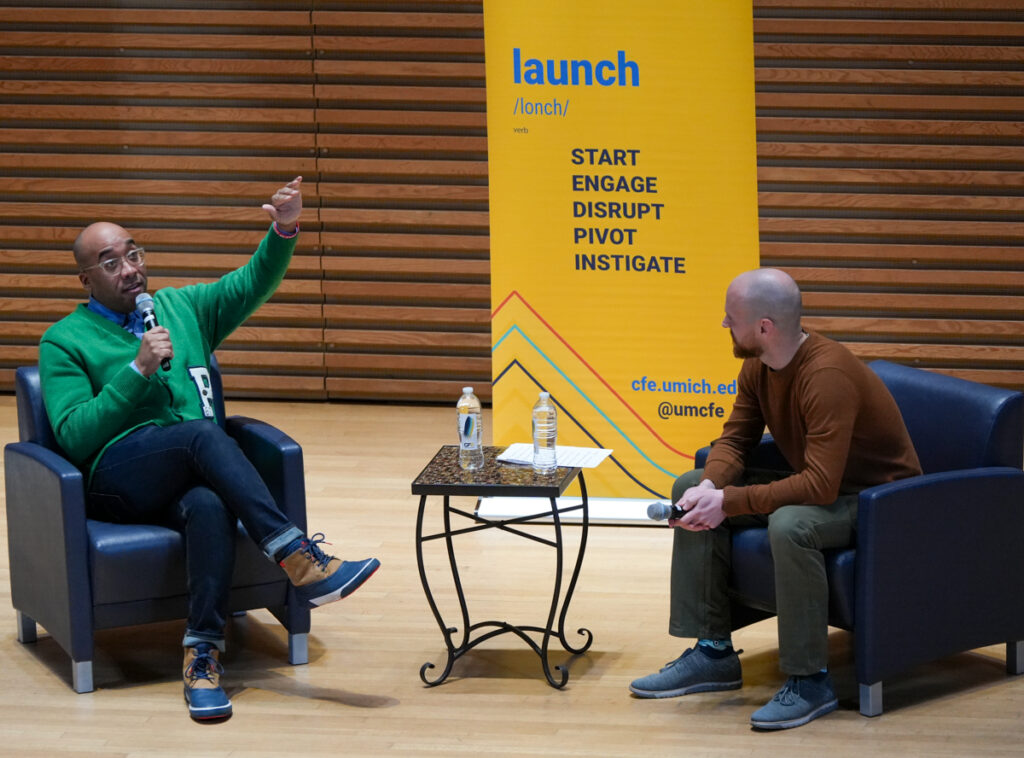 Marcus collins speaker with Eric from the CFE sitting in front of an audience giving a talk about entrepreneurship