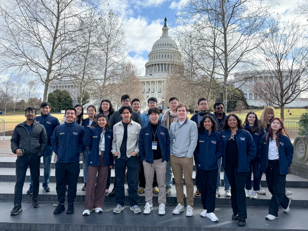 A large group of students pose in front of the Capitol building on the NEXT trek