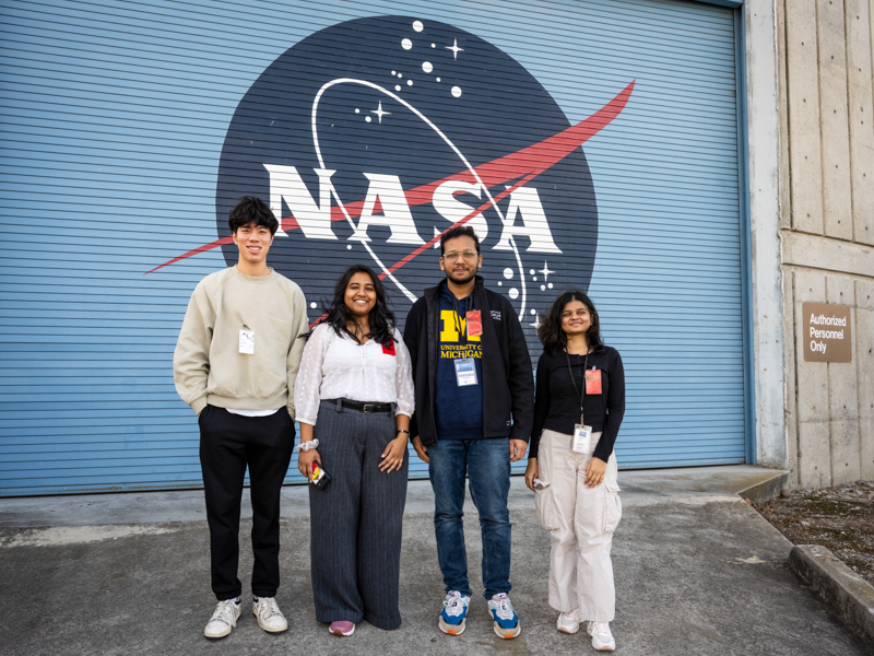 a group of four students standing in front of the NASA logo