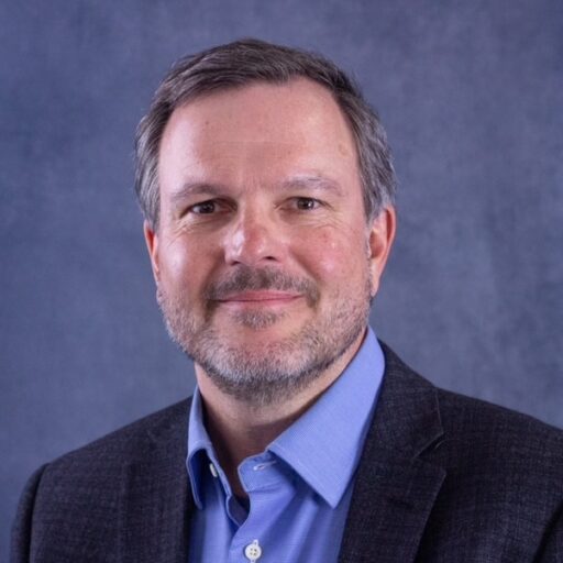 Jan Stegmann headshot with a slight beard & mustache wearing a bright blue shirt and a navy jacket