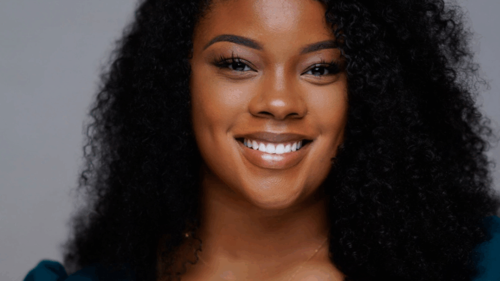 A close up of Tanisha as she smiles at the camera against a gray backdrop.