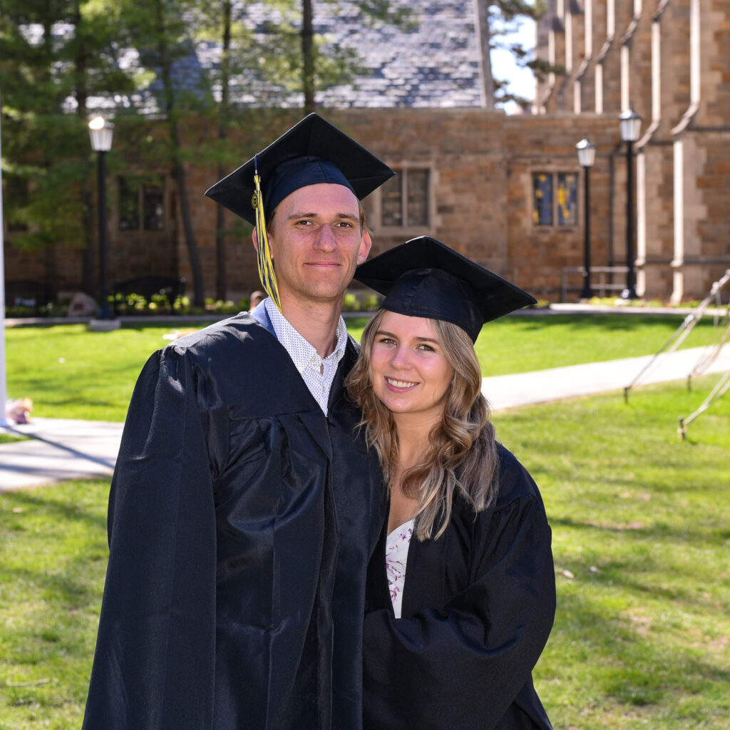 Emma and Daniil pose in their graduation cap and gowns in the University of Michigan's Law Quad.