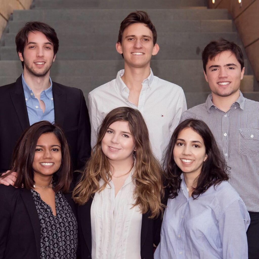 Emma and Daniil pose with fellow students in front of a large staircase.
