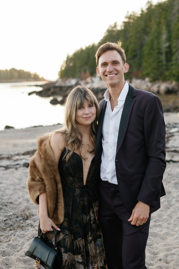 Emma and Daniil pose together on a beach, wearing fancy dress.