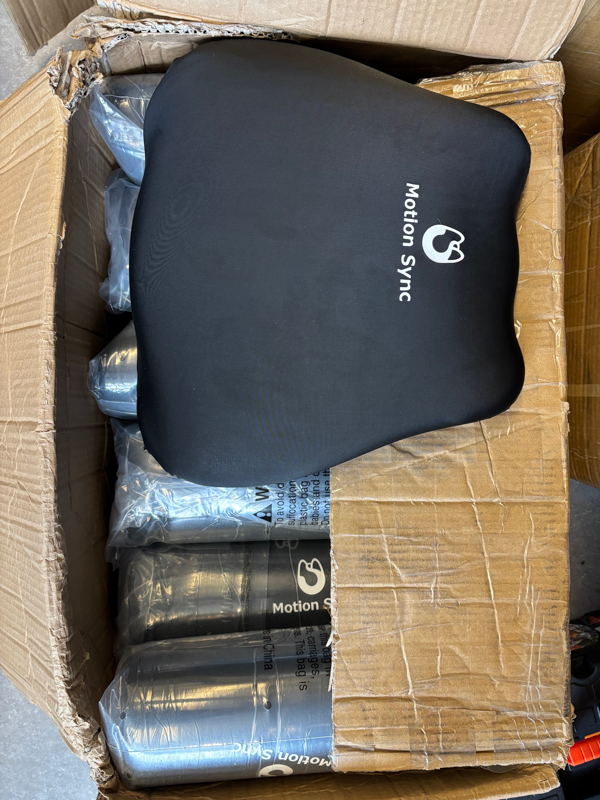 Motion sync pillow cover in black inside of a brown box with other pillow covers