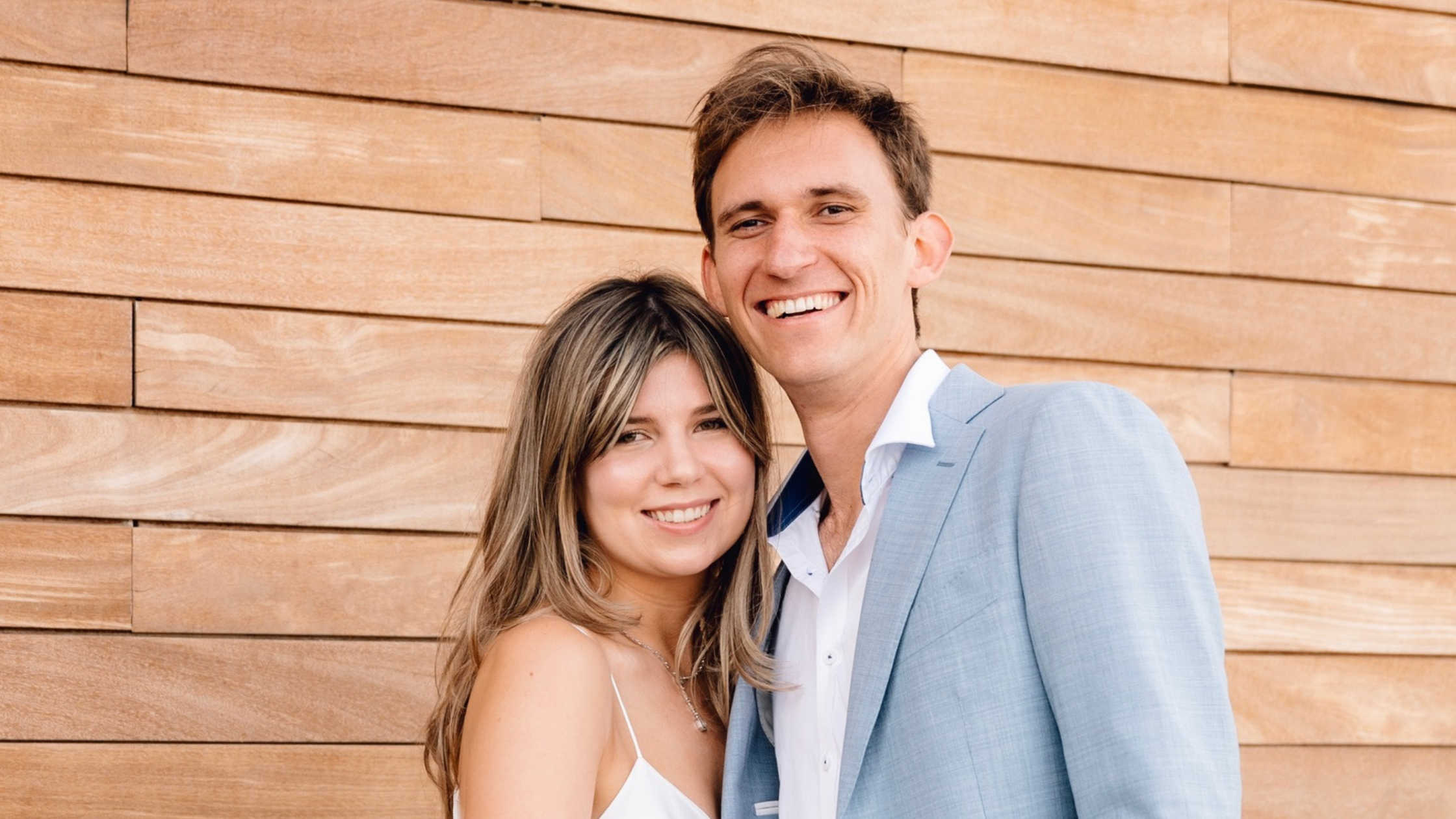 Emma Kirst and Daniil Blyum cozy up for a photo together. They are both smiling with their arms around each other, wearing elegant clothing.
