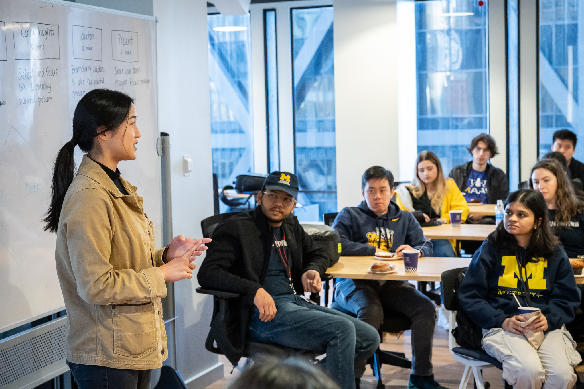 Students listen in as a speaker teaches from in front of a whiteboard.