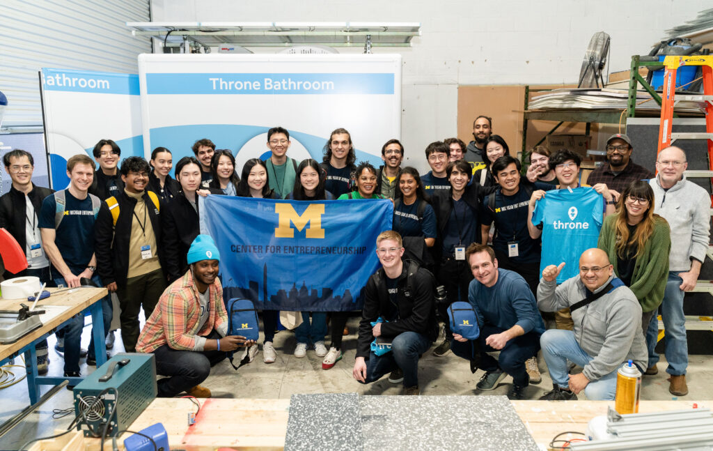 Entrepreneurship students at Michigan pose with a giant flag that reads "Center for Entrepreneurship"