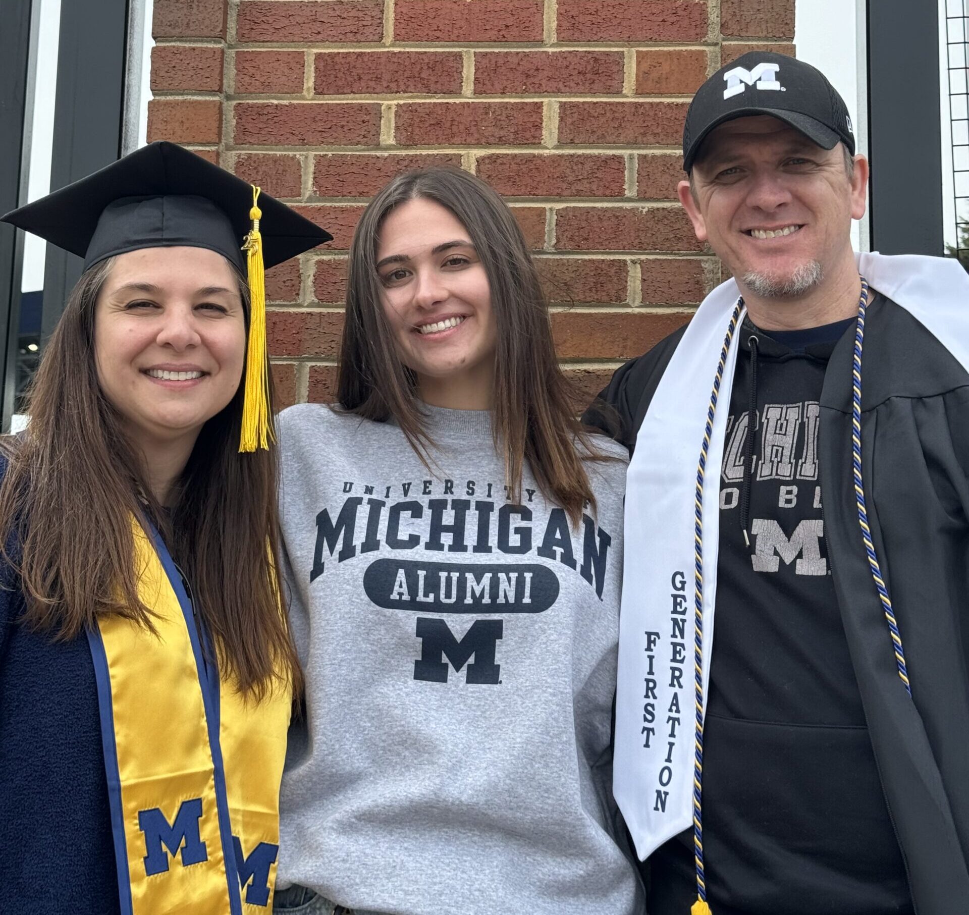 kaylin eighmey in a graduation cap and gown with her friends wearing michigan spiritwear