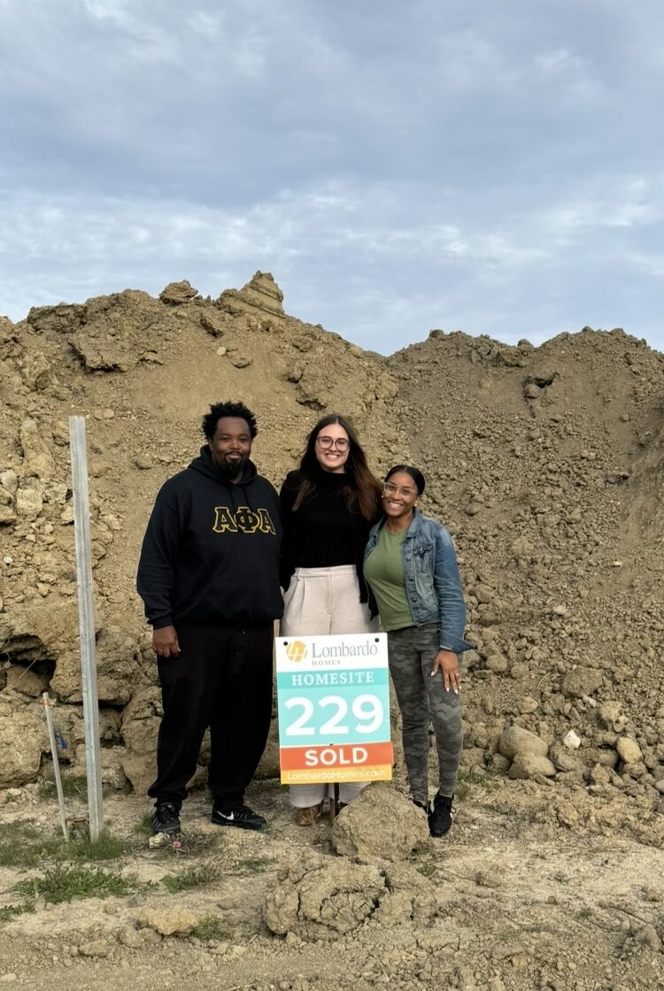 kaylin standing with her clients, at a homesite with dirt piles all around 