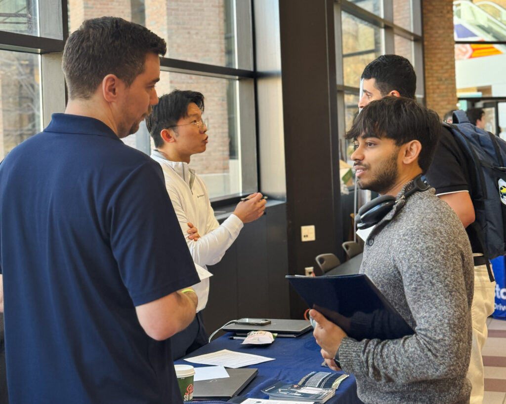 Two students are shown interacting with startup representatives at the Startup Career Fair.