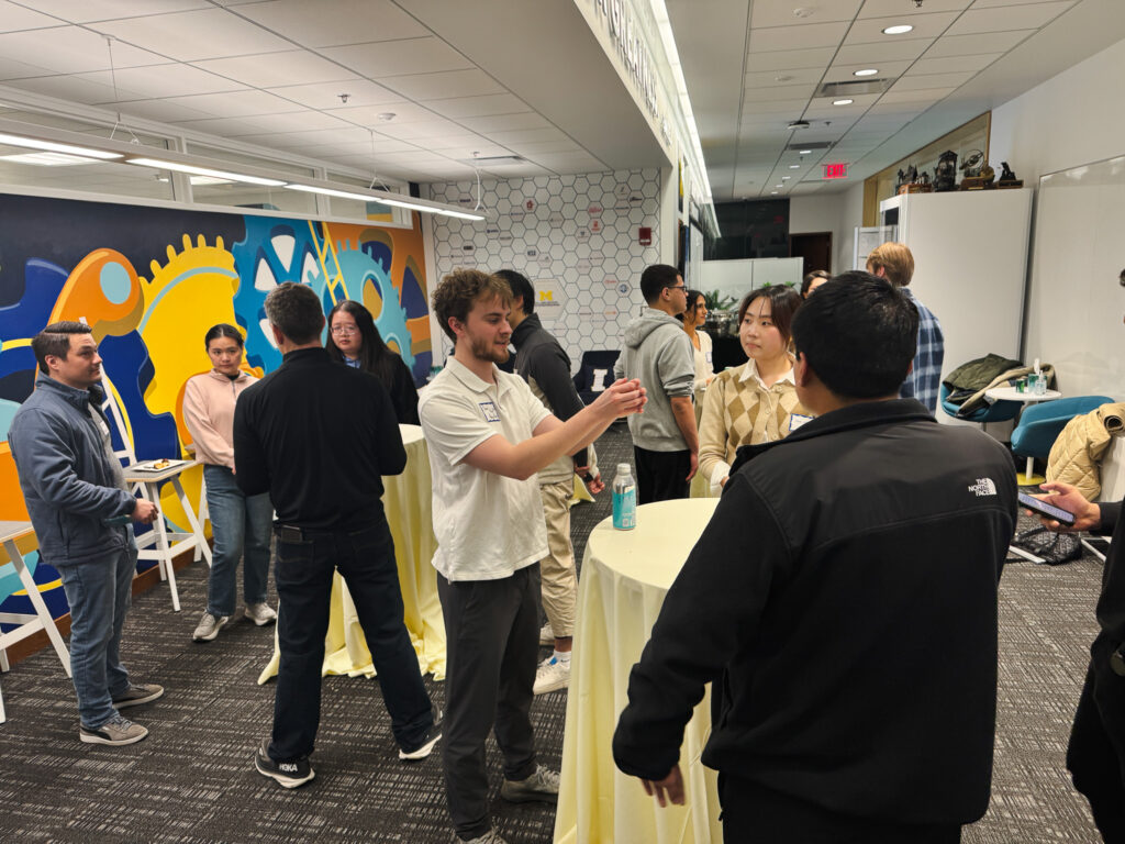  Students and startup representatives are seen networking around small tables with yellow tablecloths at the Startup Career Fair.