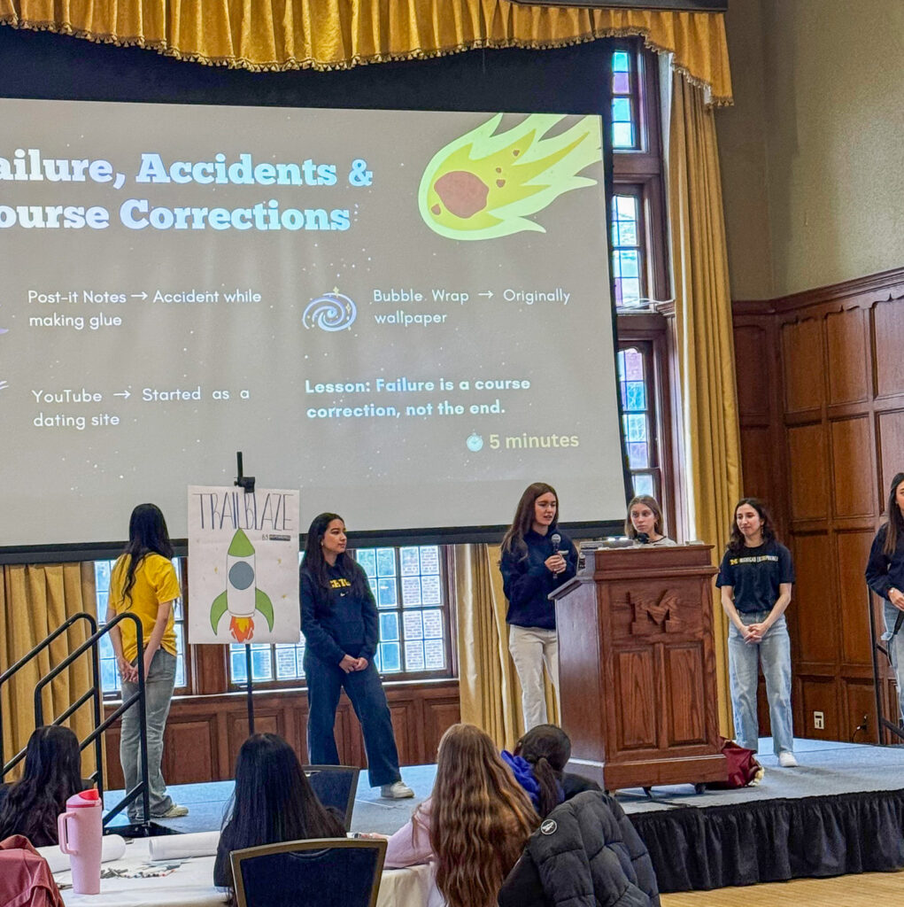 a group of entrepreneurial students giving a presentation to middle schoolers
