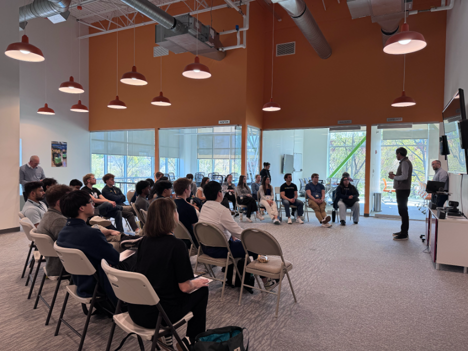 students sitting in folding chairs while a speaker addresses the room