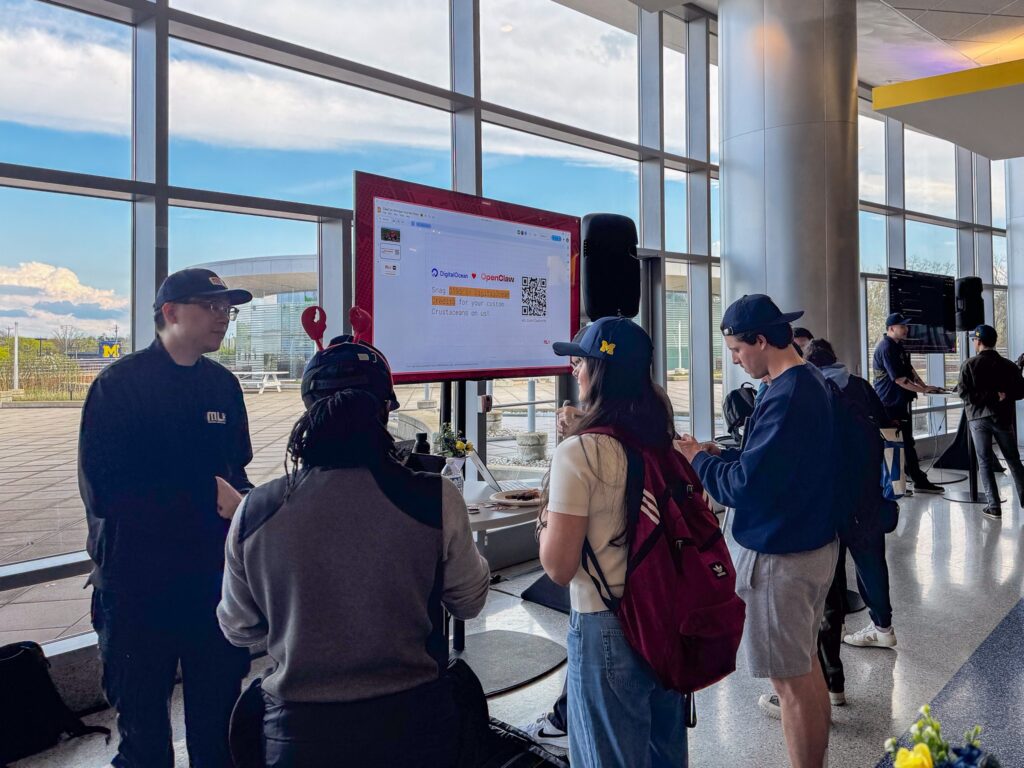 Students crowd around a booth at ClawCon, listening intently to the attendant as they describe agentic AI methods.