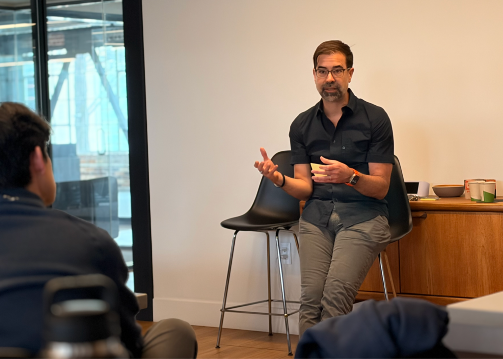 a man in glasses using his hands to gesture during a talk with studens