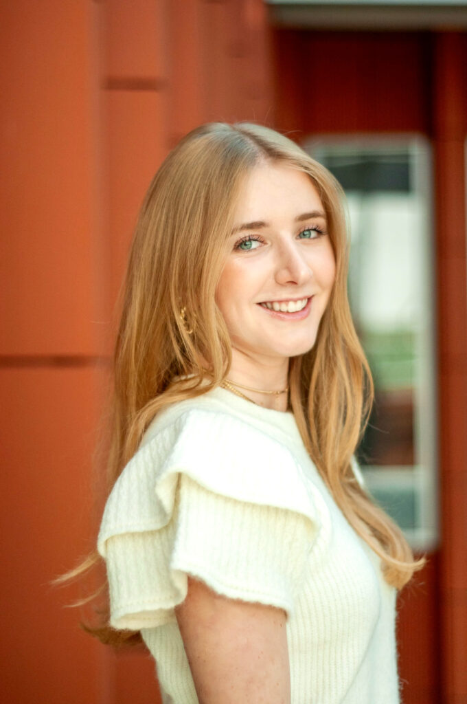 Julia smiles for a headshot against the orange walls of Ross School of Business