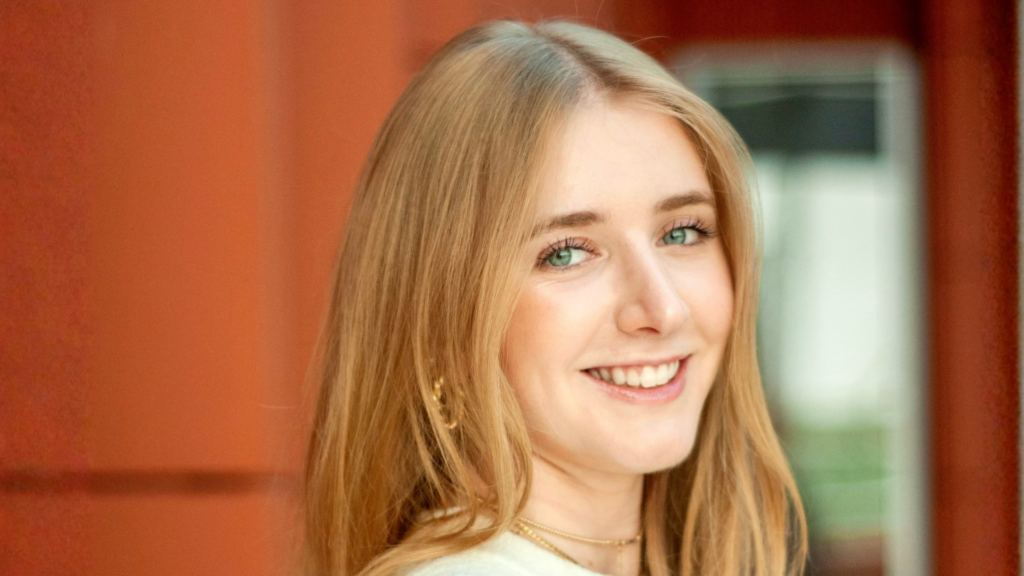 Julia smiles for a headshot against the orange walls of Ross School of Business