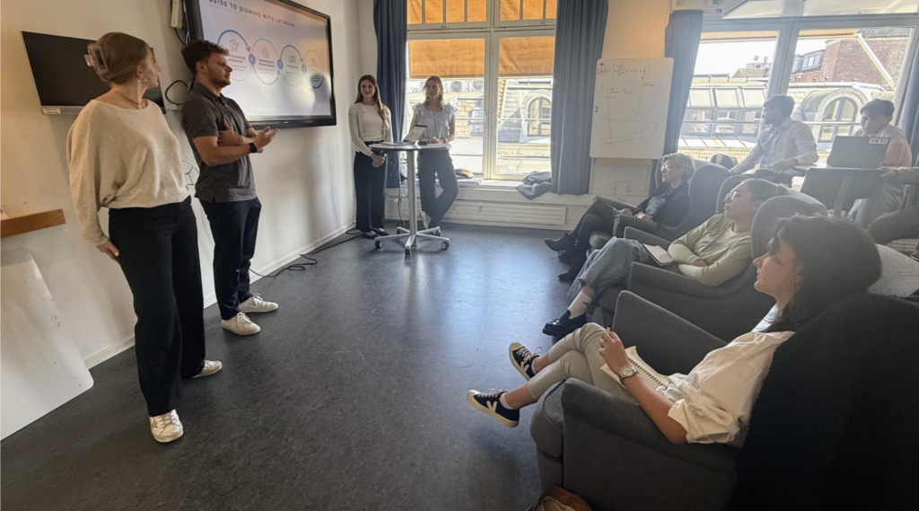 Students are shown pitching to fellow students and judges. 
