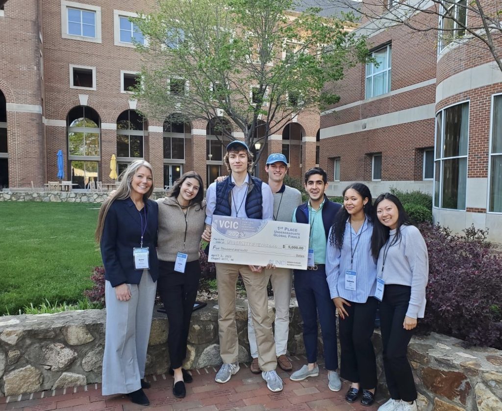Arjan poses with a group of fellow students holding a giant check